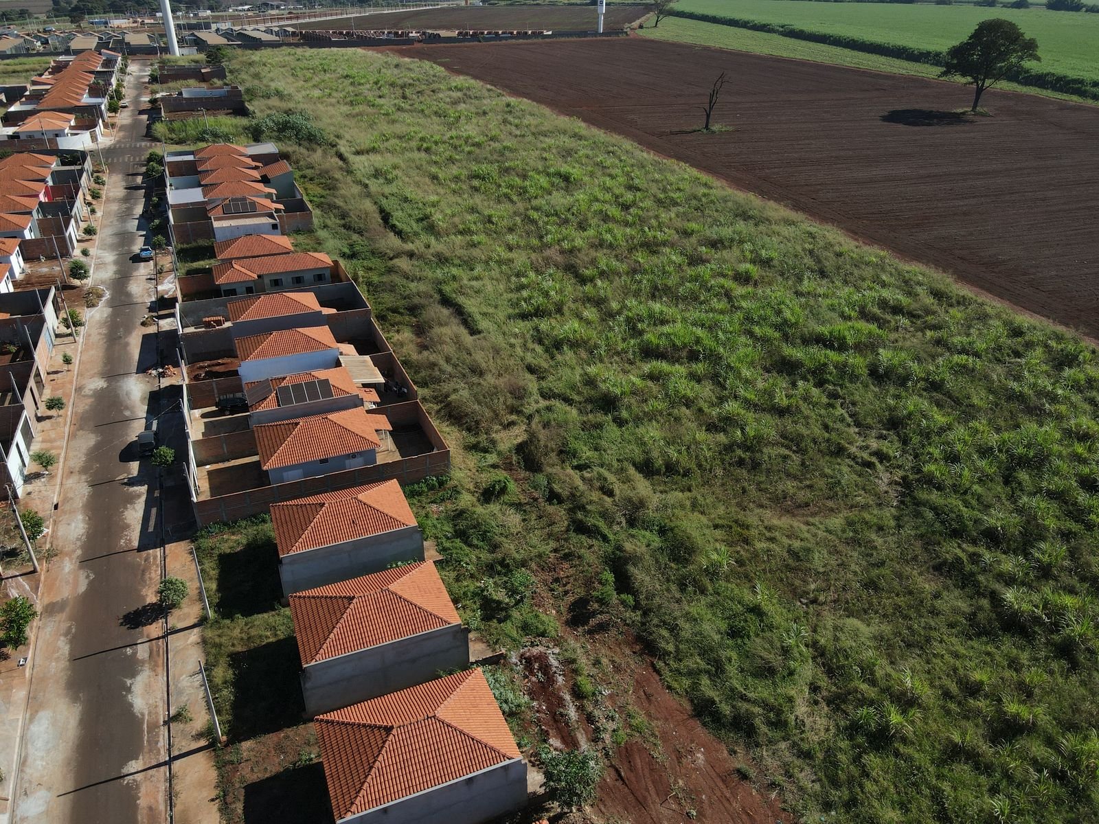 Vista aérea antes do loteamento: bairro existente e gleba vazia ao lado